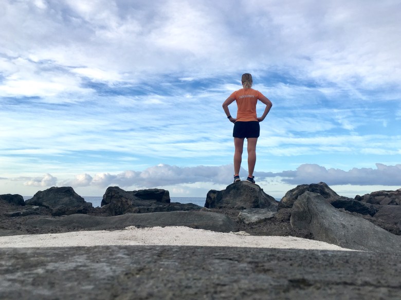 Kuva, jossa nainen seisoo kivella ja katsoo horisonttiin.