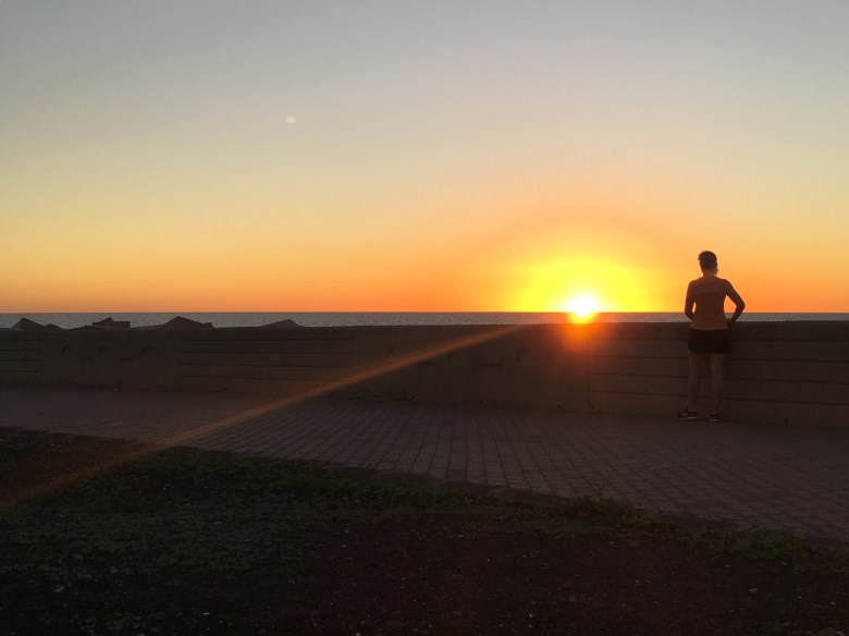 Kuva, jossa juoksija katsoo laskevaa aurinkoa.