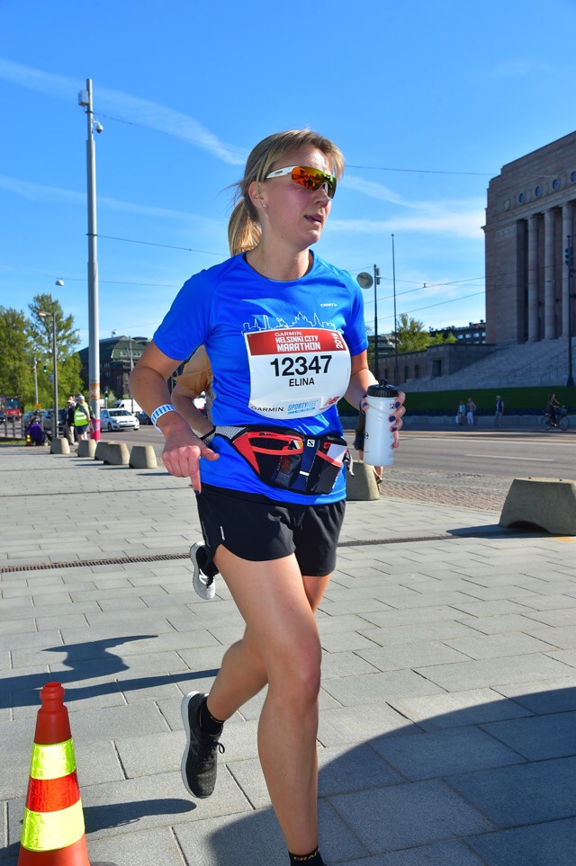 Kuva, jossa maratonjuoksija eduskuntatalon edessä.