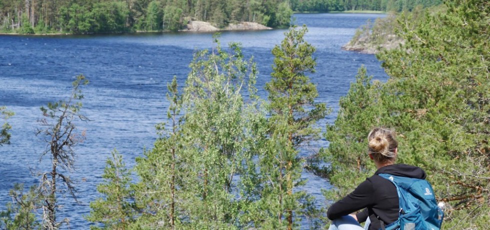 Kuva, jossa retkeilija istuu kalliolla.