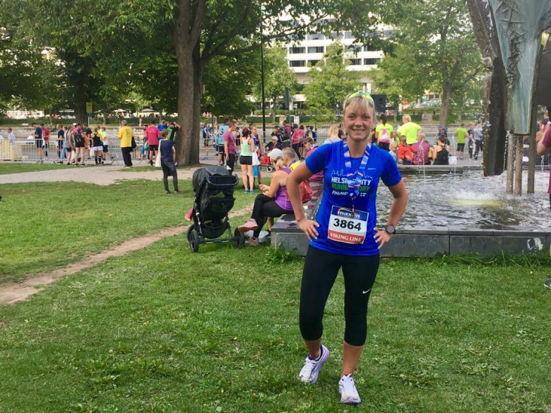 Kuva, jossa juoksja mitali kaulassa.