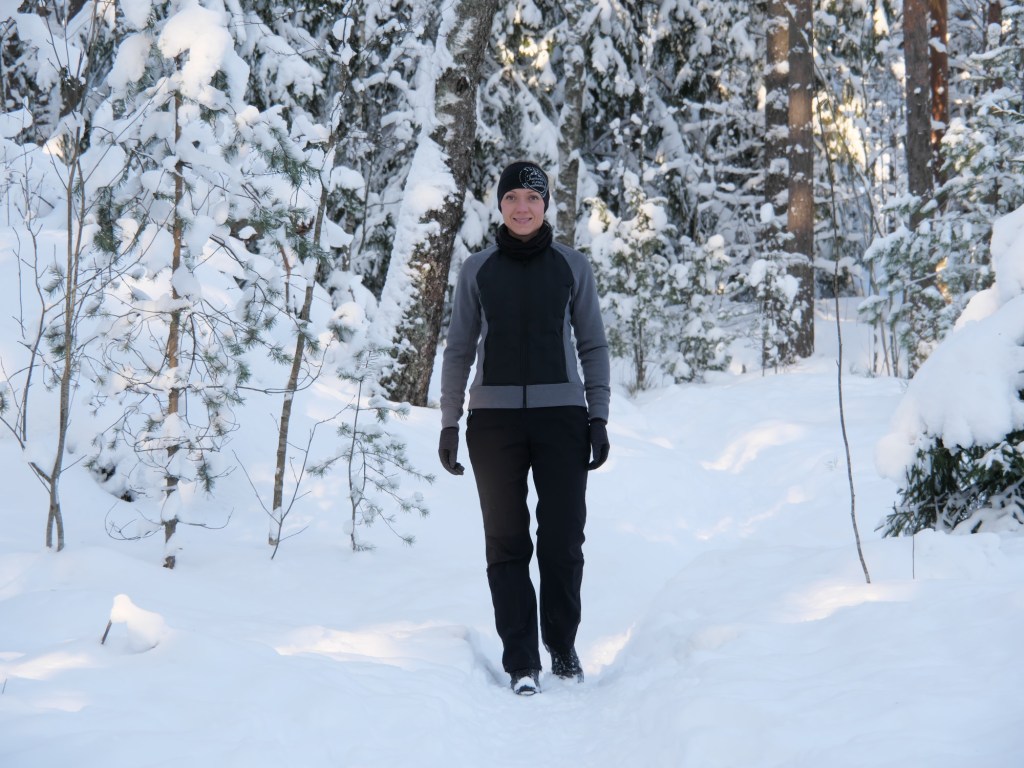 kuva, jossa nainen kavelee lumisessa metsassa