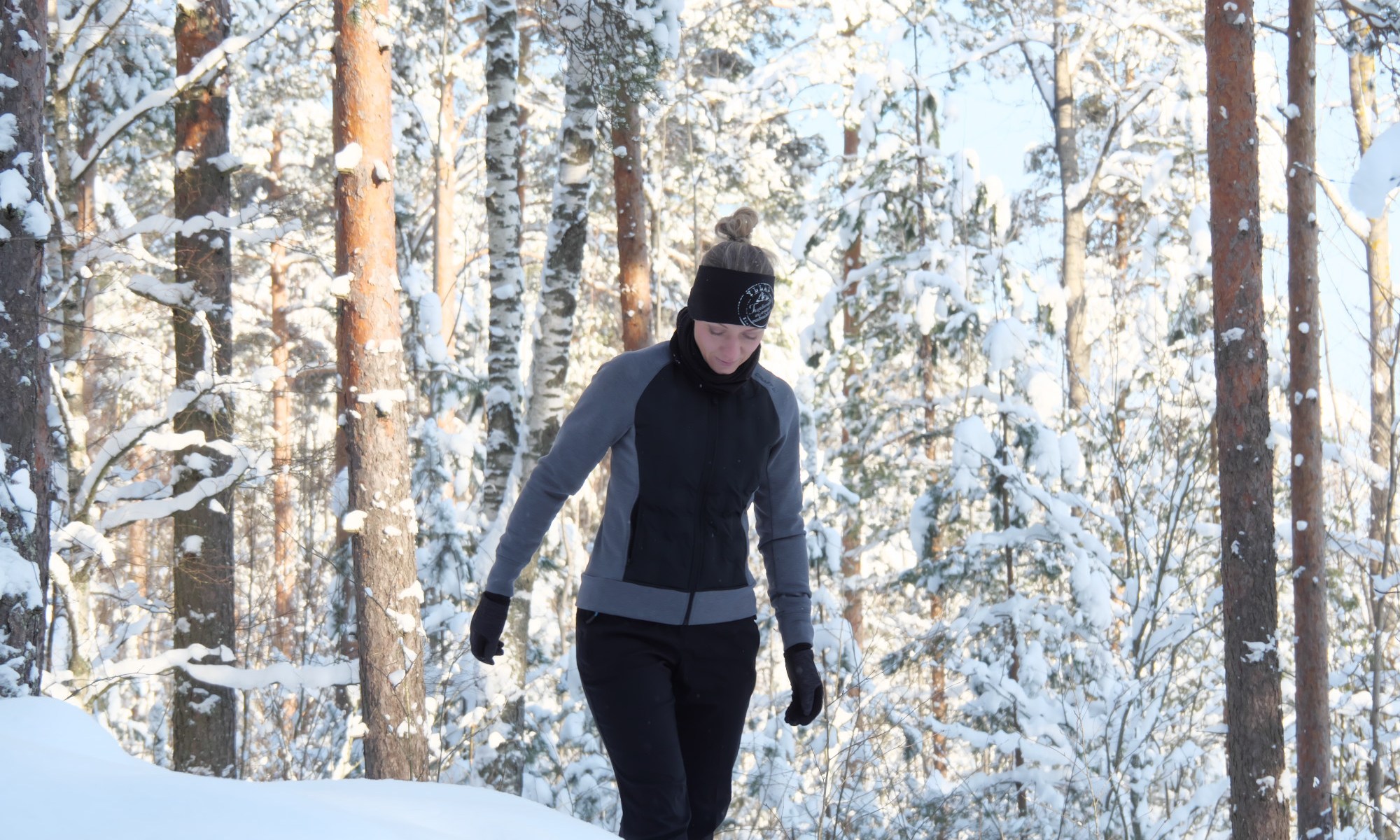 kuva, jossa nainen kavelee lumisessa metsassa