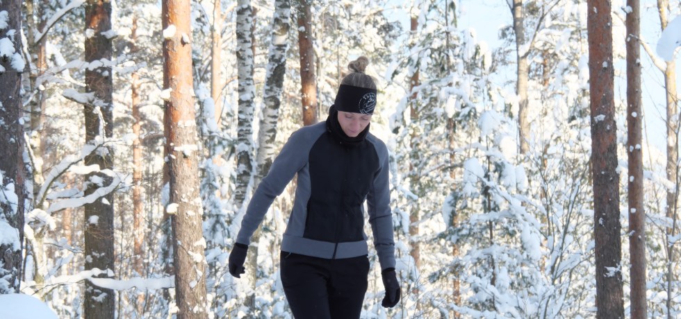 kuva, jossa nainen kavelee lumisessa metsassa