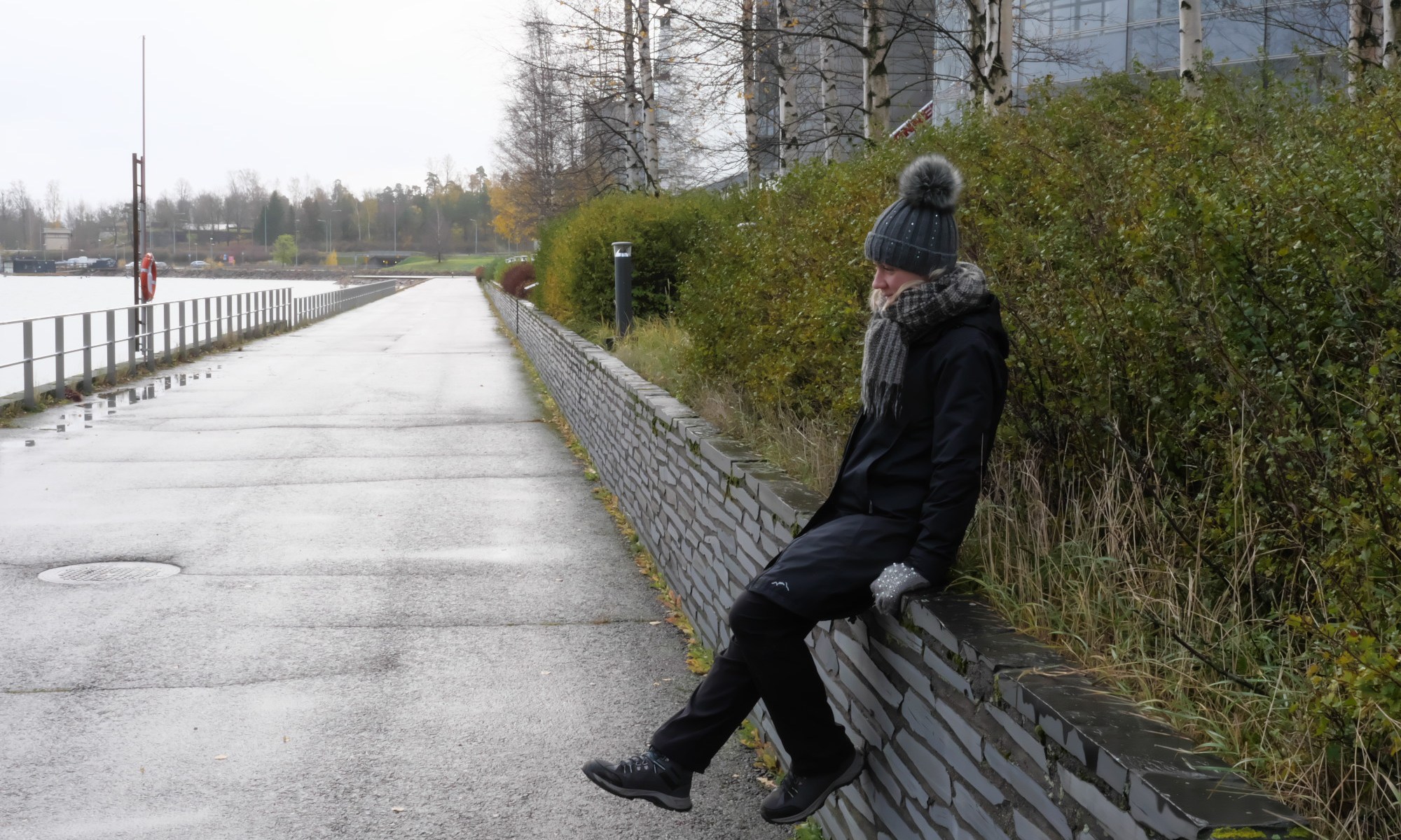 nainen istuu kiviaidan paalla