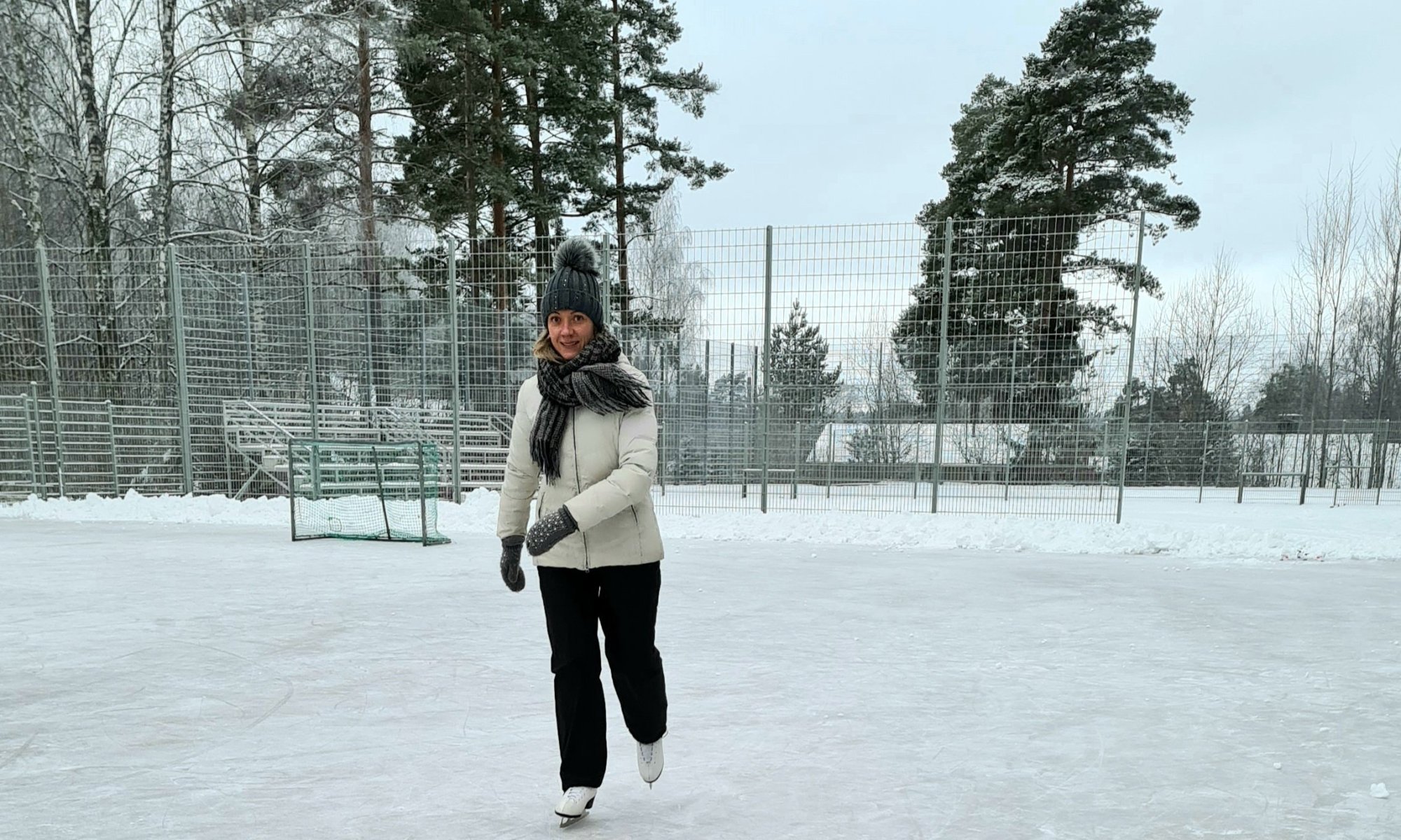 nainen luistelee valkoisessa toppatakissa