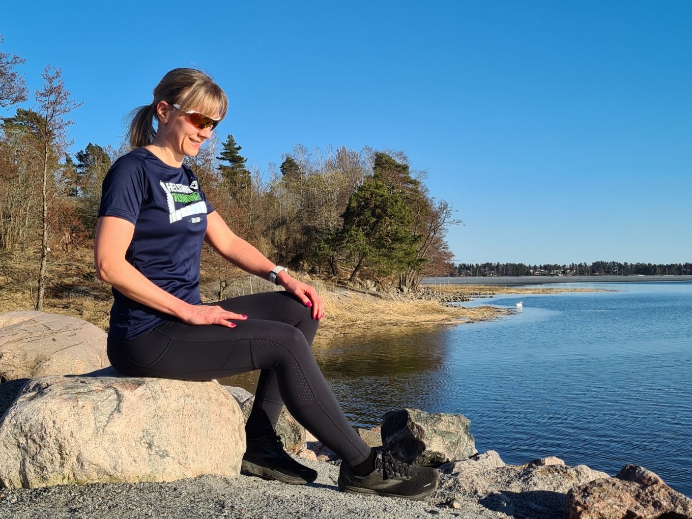 juoksija istuu rantakivella t-paita paalla