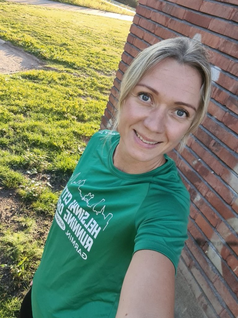 juoksija nojaa tiiliseinaan ja hymyilee