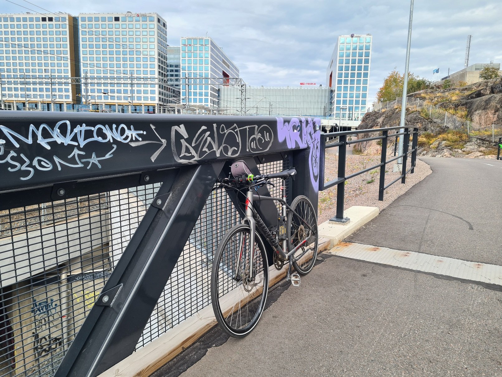 polkupyora nojaa kaiteeseen, takana kauppakeskus tripla