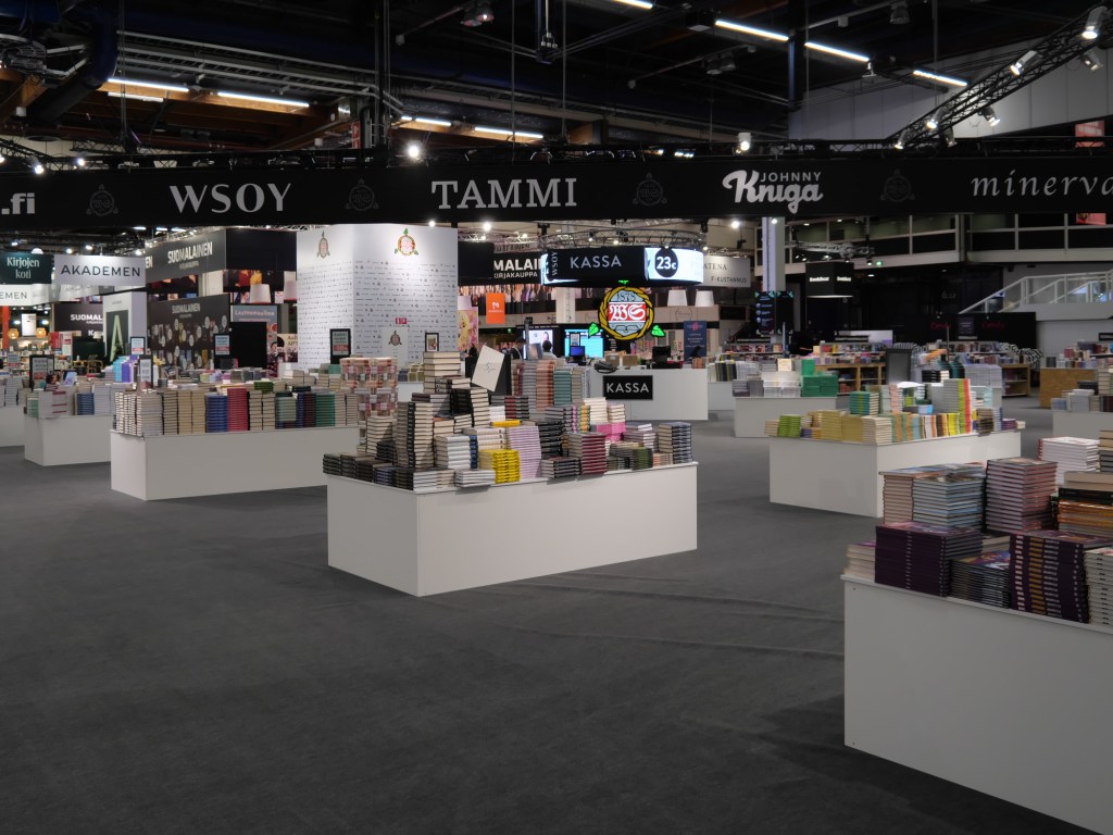 Sain tapahtumaan somevaikuttajapassin, jolla pääsen osallistumaan messuille jokaisena neljänä aukiolopäivänä. Avajaispäivänä torstaina kävin vain nopeasti aamulla hakemassa passini ja aistimassa avajaispäivän tunnelmaa. Messukeskuksen avariin tiloihin levittäytyneet kirjakustantamojen ja kirjakauppojen osastot olivat valmiina vastaanottamaan tuhannet vierailijat.