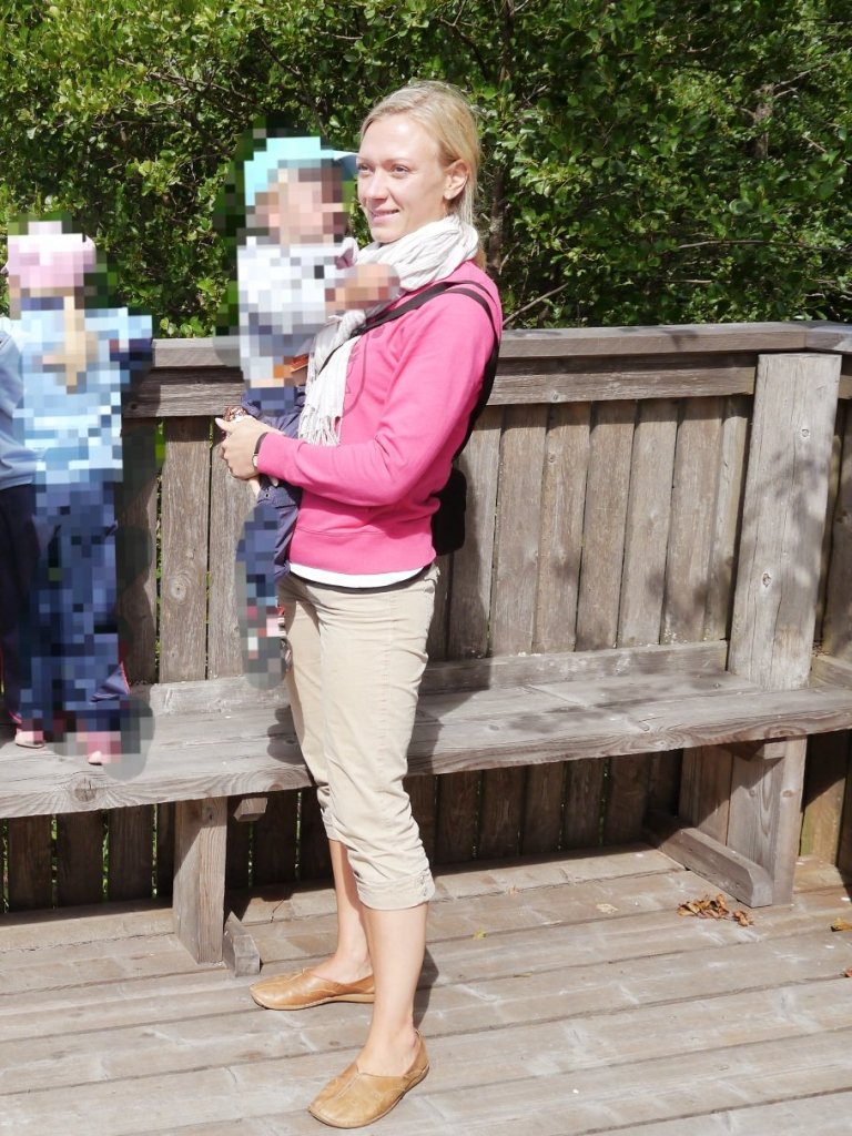 Naisen seisoo lintutornissa ja pitaa lasta sylissaan.