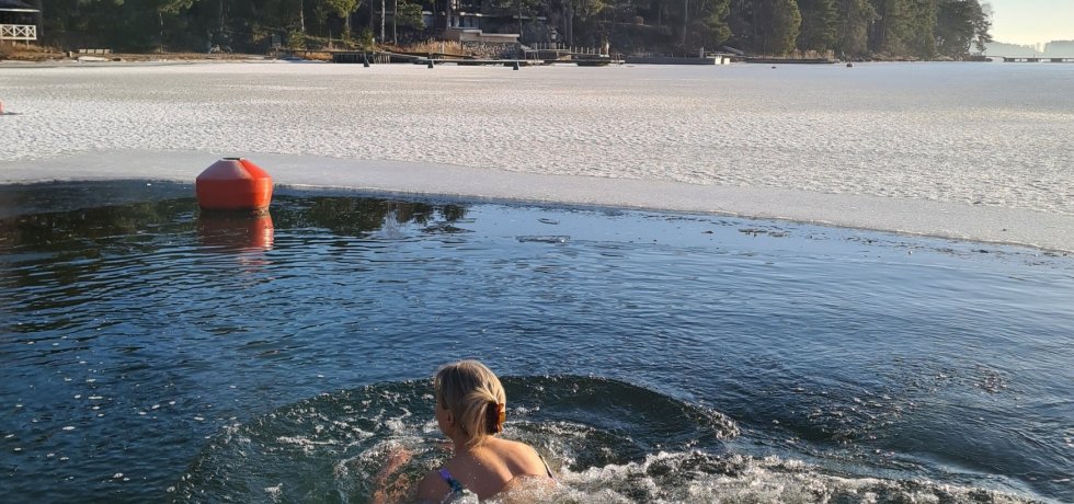 nainen ui avannossa helmikuussa ja aurinko paistaa