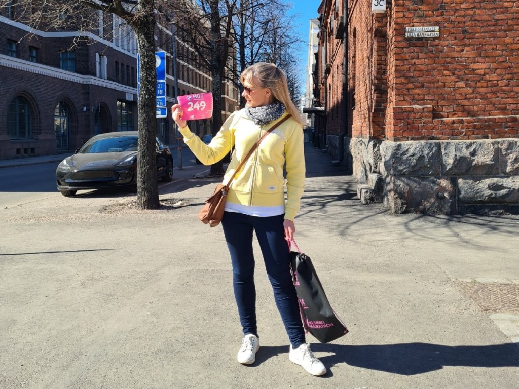 juoksija poseeraa numerolappu kadessaan