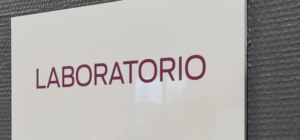 valkoinen laboratorio kyltti harmaalla seinalla