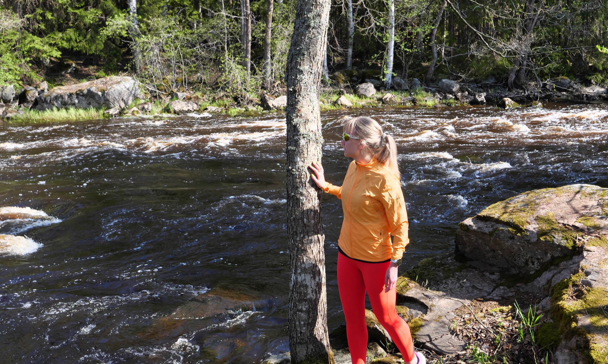 nainen katsoo joen rannassa veteen