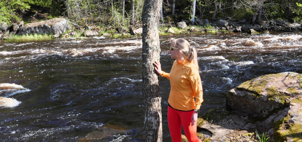 nainen katsoo joen rannassa veteen