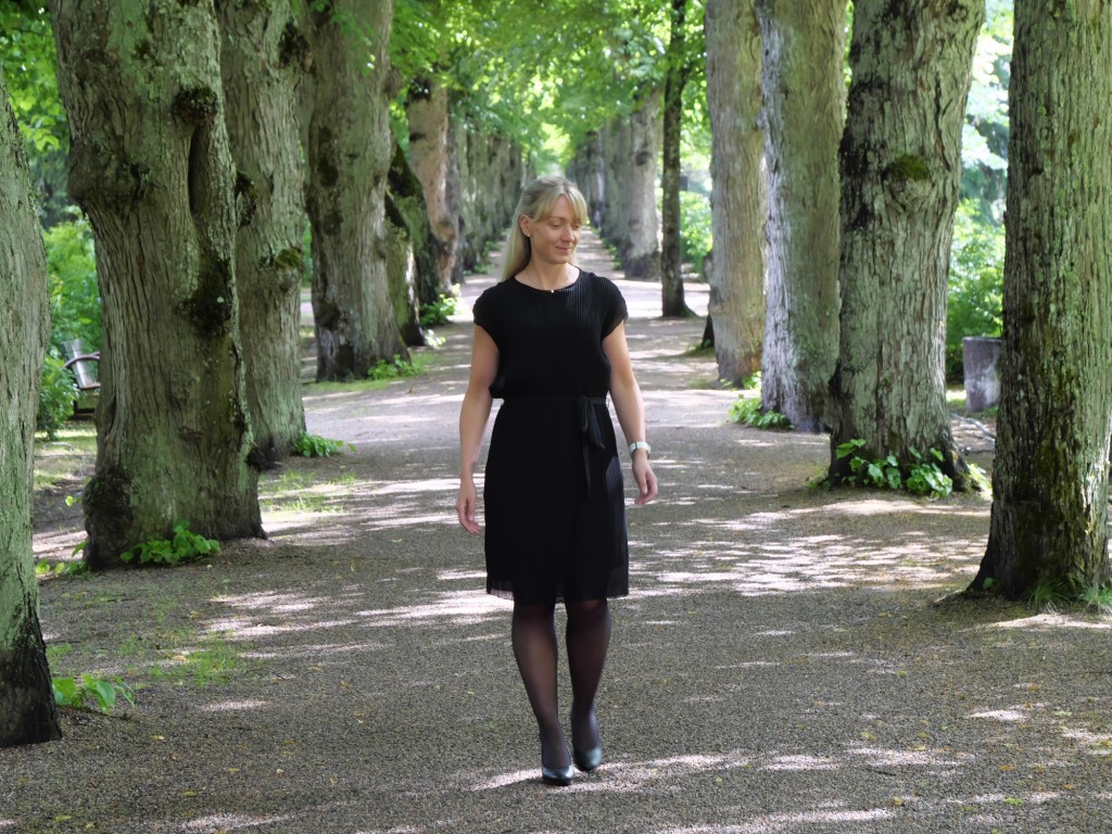 nainen kavelee pitkin lehmuskujaa