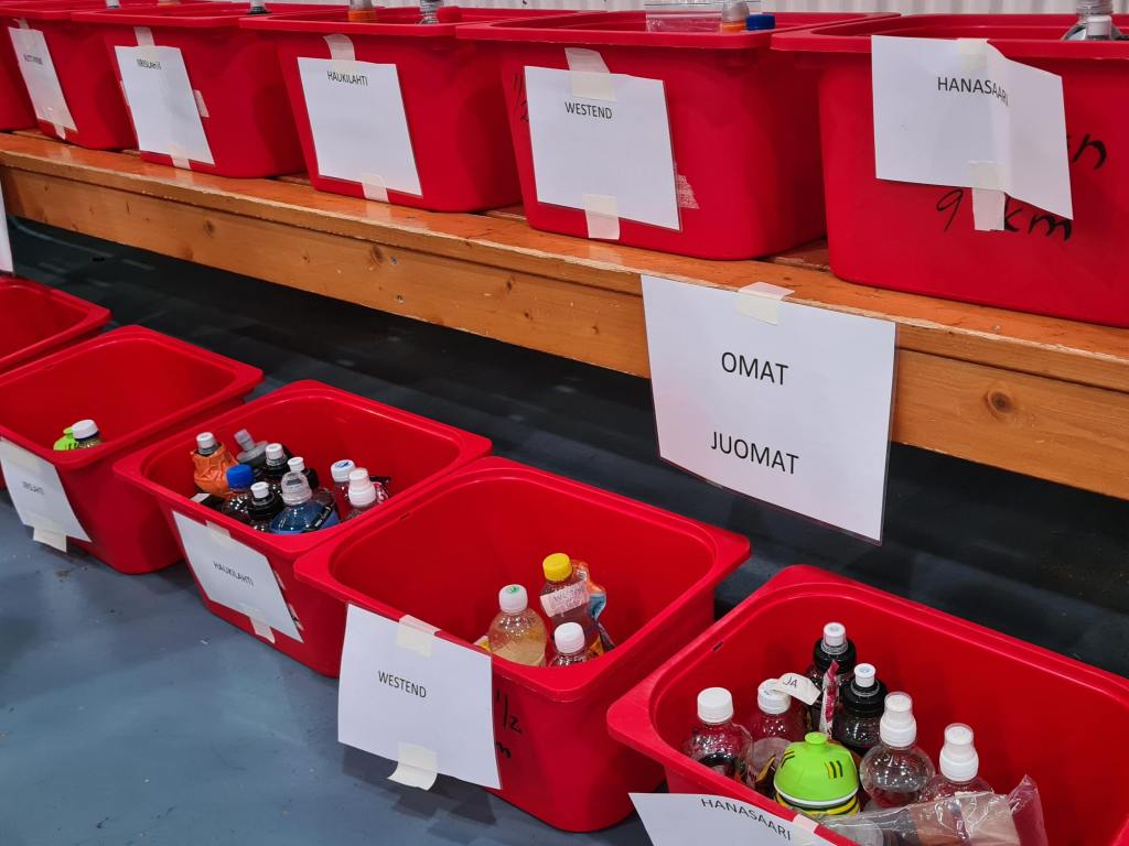 punaisia laatikoita joissa juoksijoiden omia juomapulloja