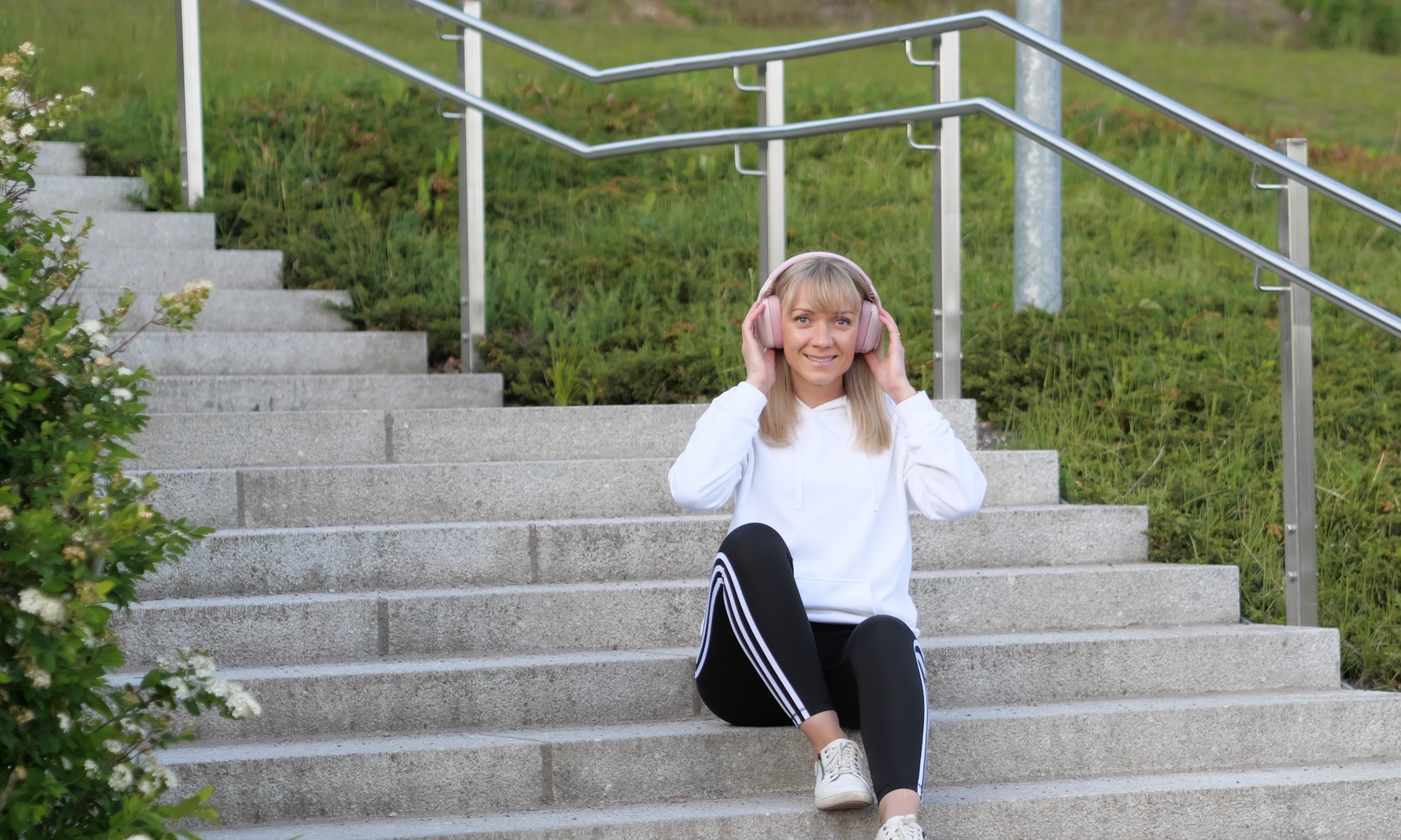 nainen istuu portailla valkoisessa hupparissa