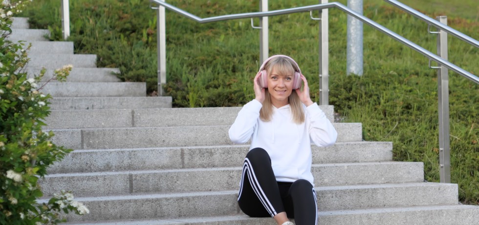 nainen istuu portailla valkoisessa hupparissa