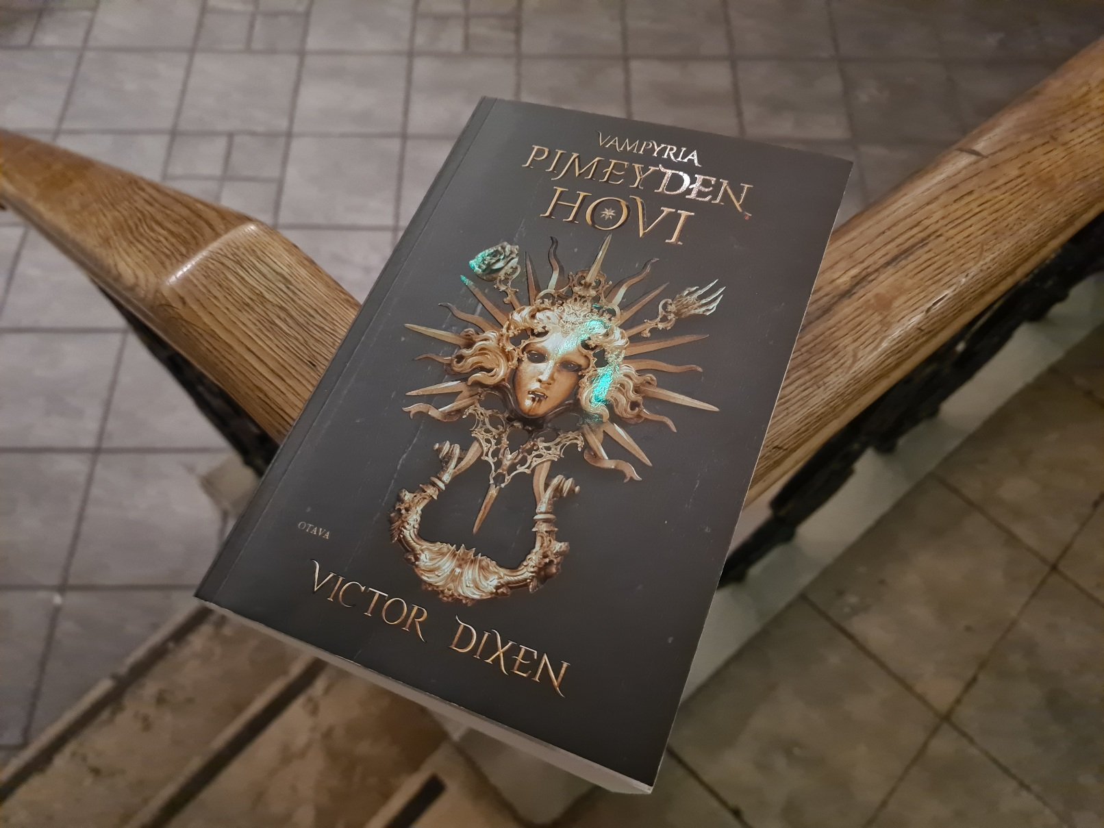 pimeyden hovi pokkari aseteltuna kaiteen paalle