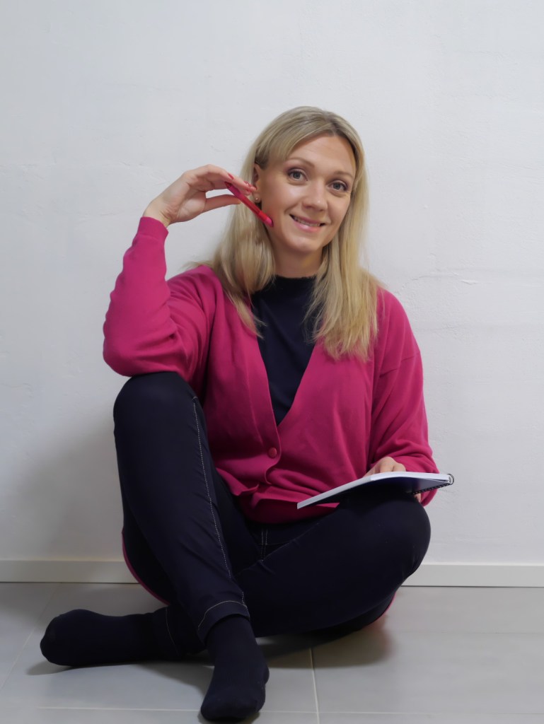 nainen istuu lattialla kirjoittamassa