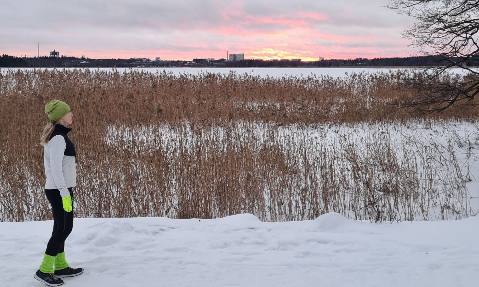 juoksija katselee laskevaa aurinkoa talvella merenrannassa