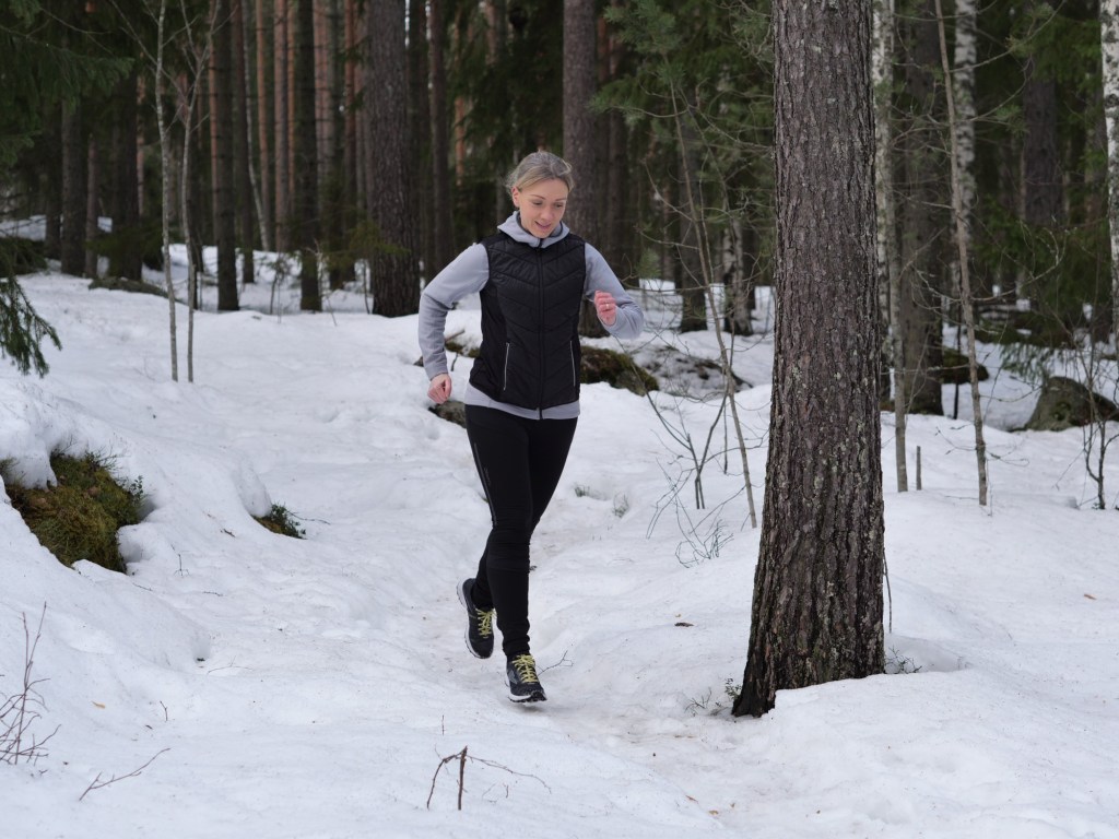polkujuoksija lumisessa metsassa