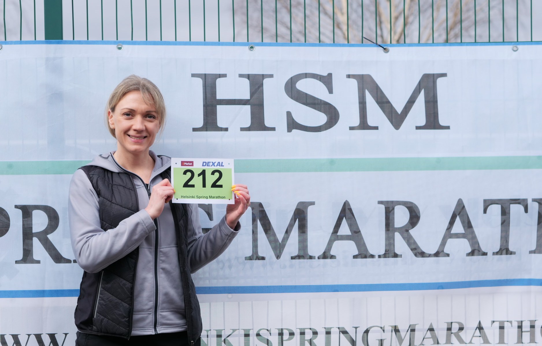 nainen seisoo mainosjulisteen edessa