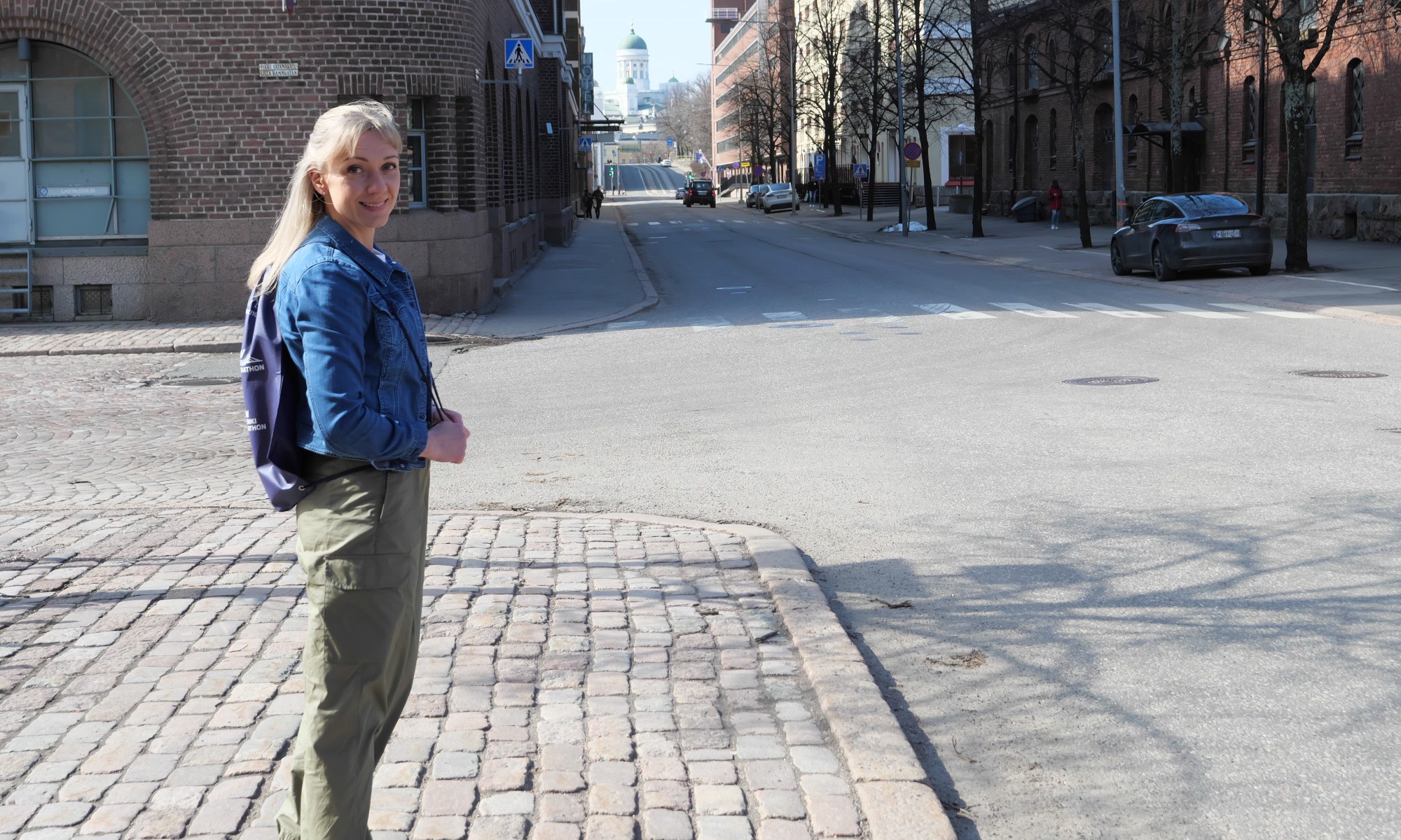 nainen seisoo kadulla helsingin katajanokalla ja taustalla nakyy tuomiokirkko