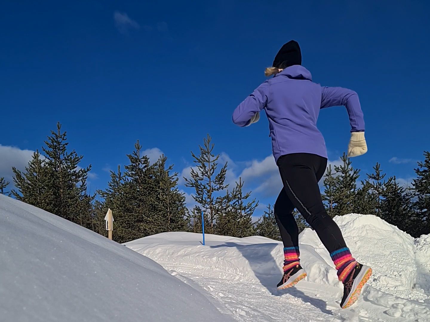 juoksija juoksee pitkin lumista polkua lapissa