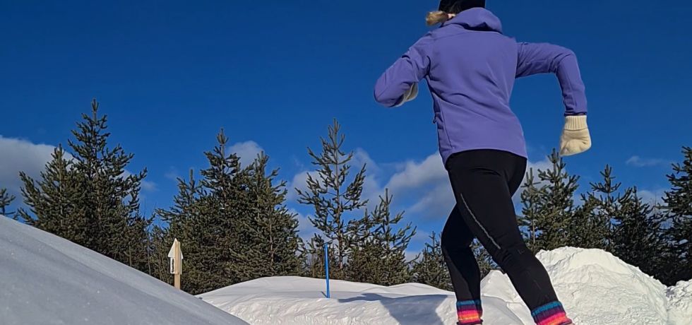 juoksija juoksee pitkin lumista polkua lapissa