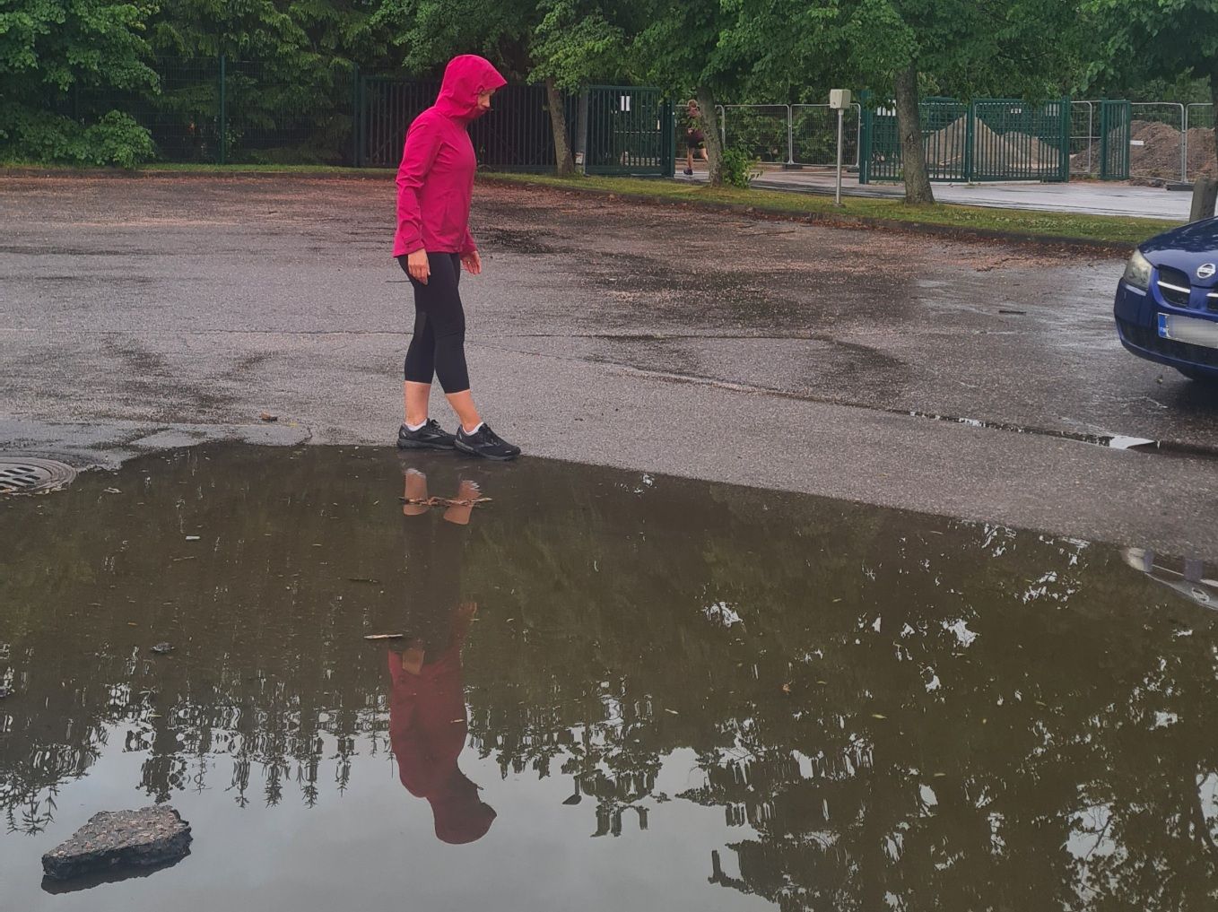 juoksija kavelee sateisena paivana vesilammikon vieresta