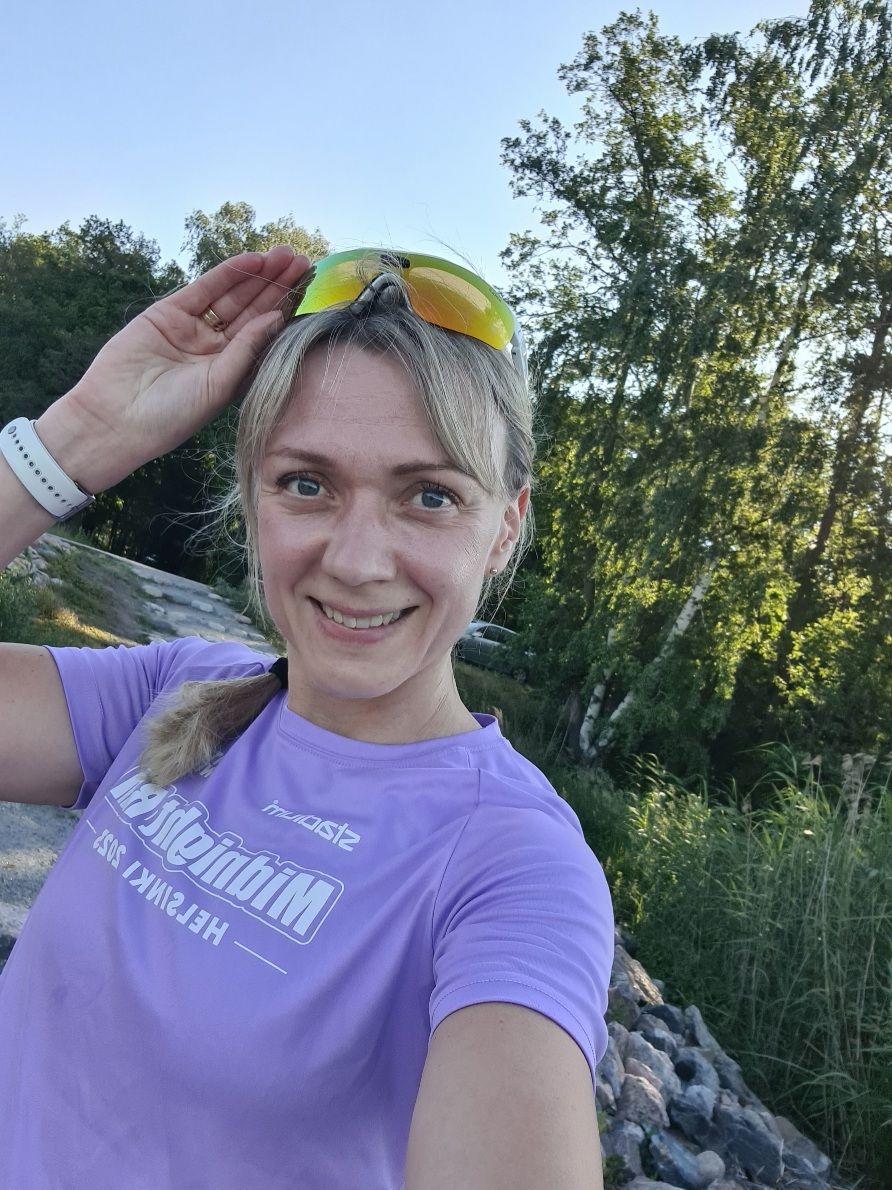 juoksija nostaa aurinkolaseja silmiltaan ja hymyilee kameralle