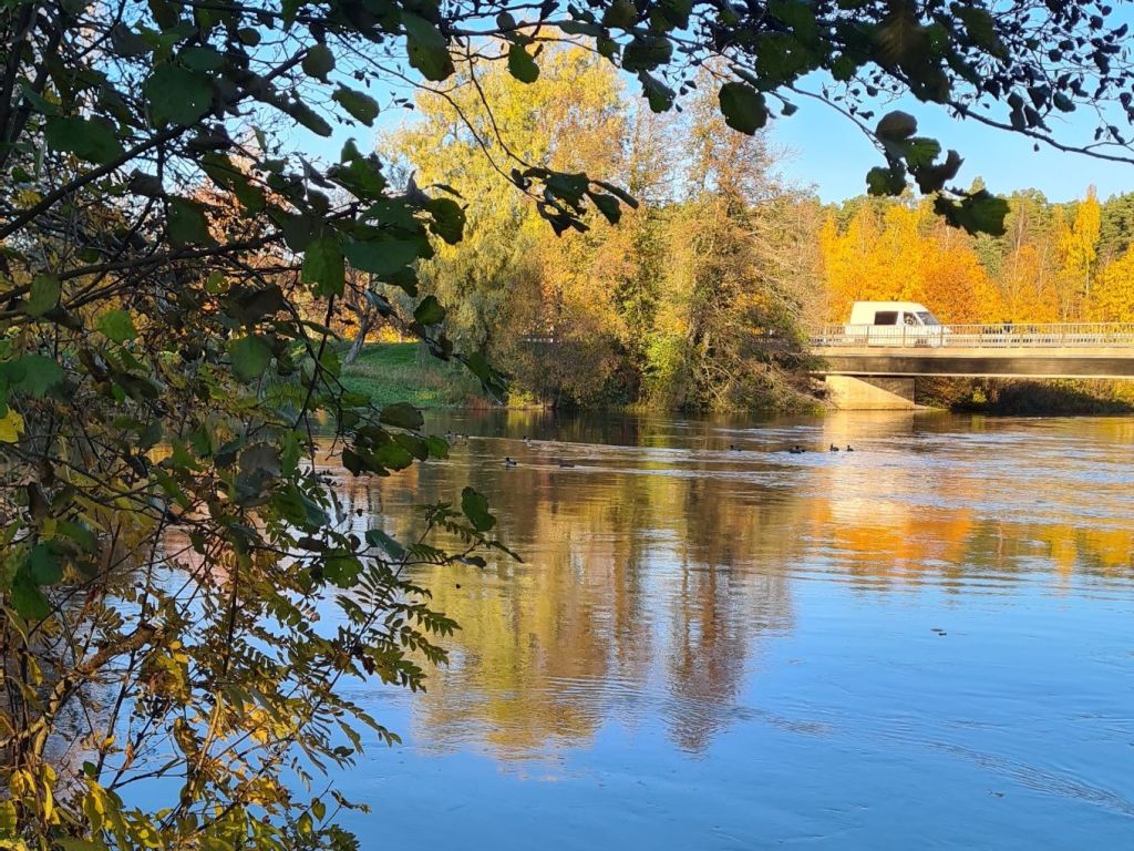 valkoinen pakettiauto ajaa sillalla ja vesi virtaa alla