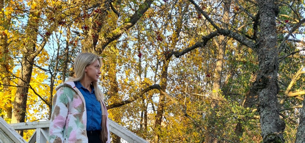 nainen kavelee puusillalla ja puissa on ruska