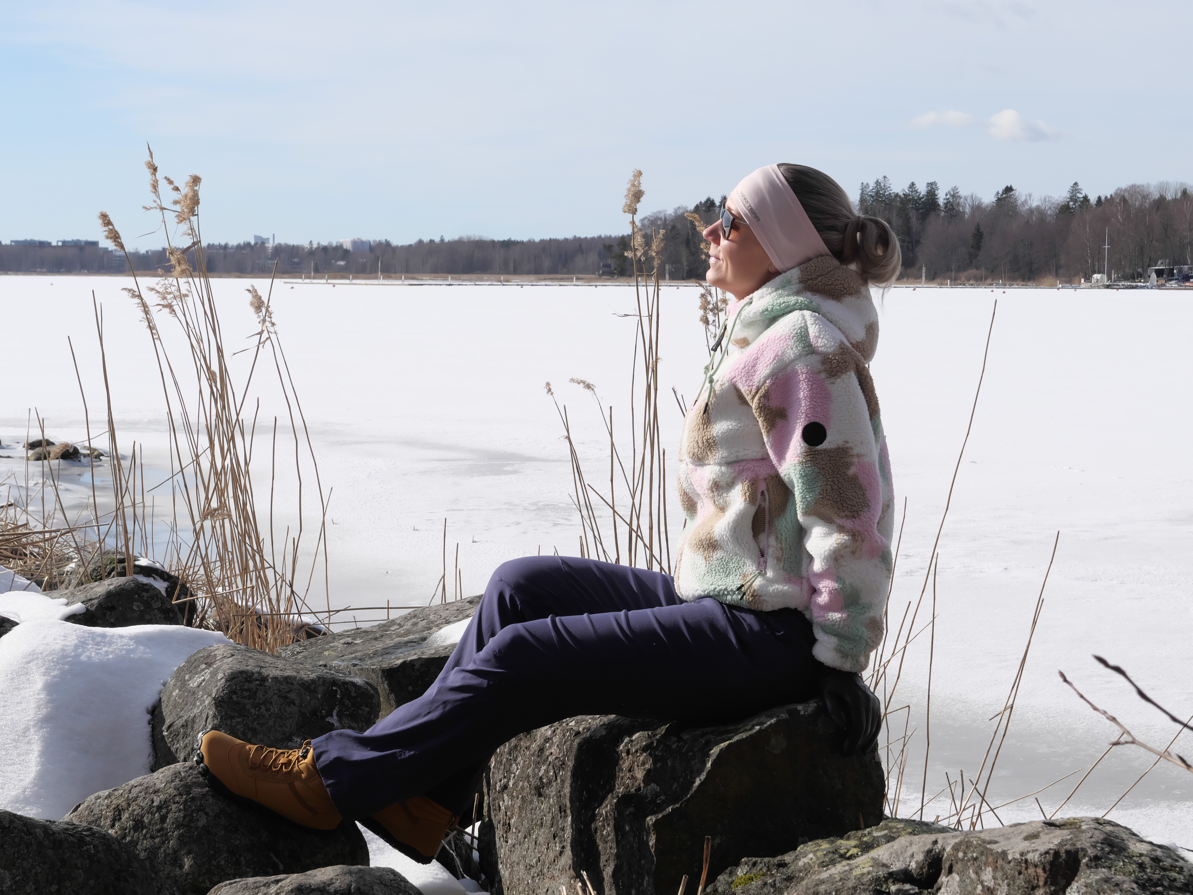nainen istuu rantakivella kevatauringossa