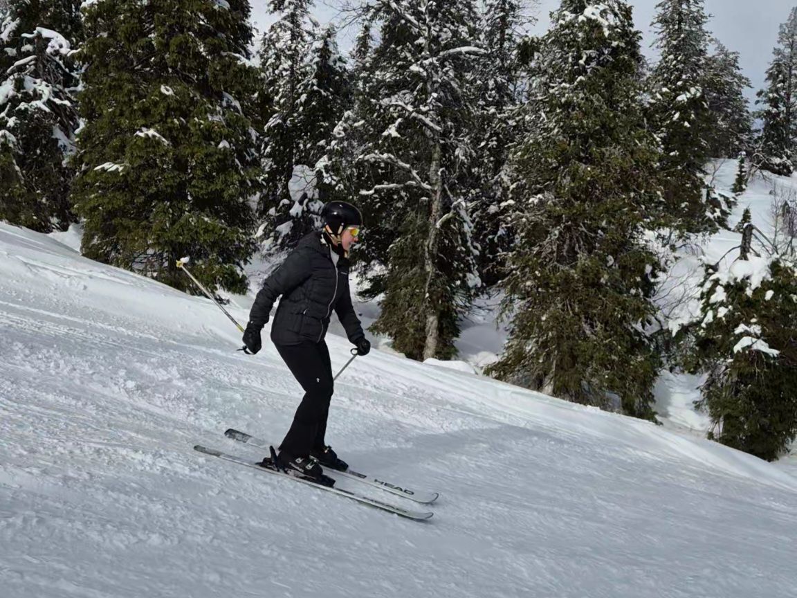 nainen laskee tummassa laskettelupuvussa alas tunturin rinnetta