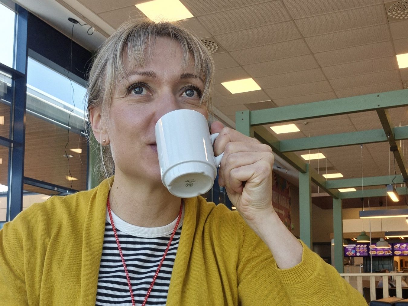 naisella on kadessaan valkoinen kahvikuppi