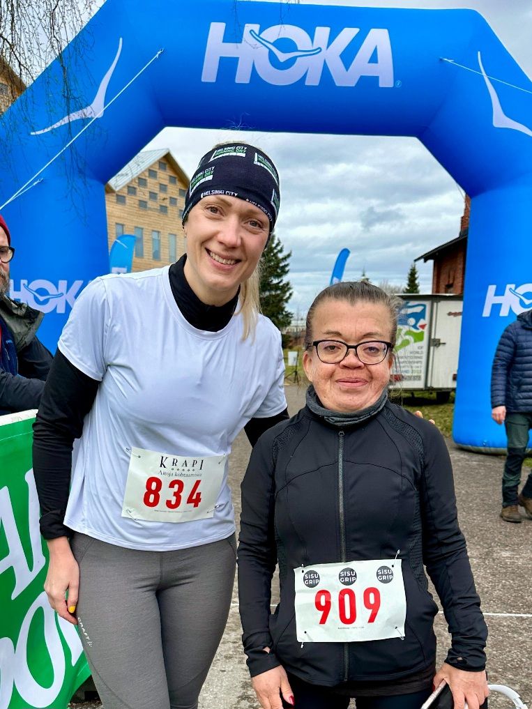 kaksi naisjuoksijaa maalikaaren alla