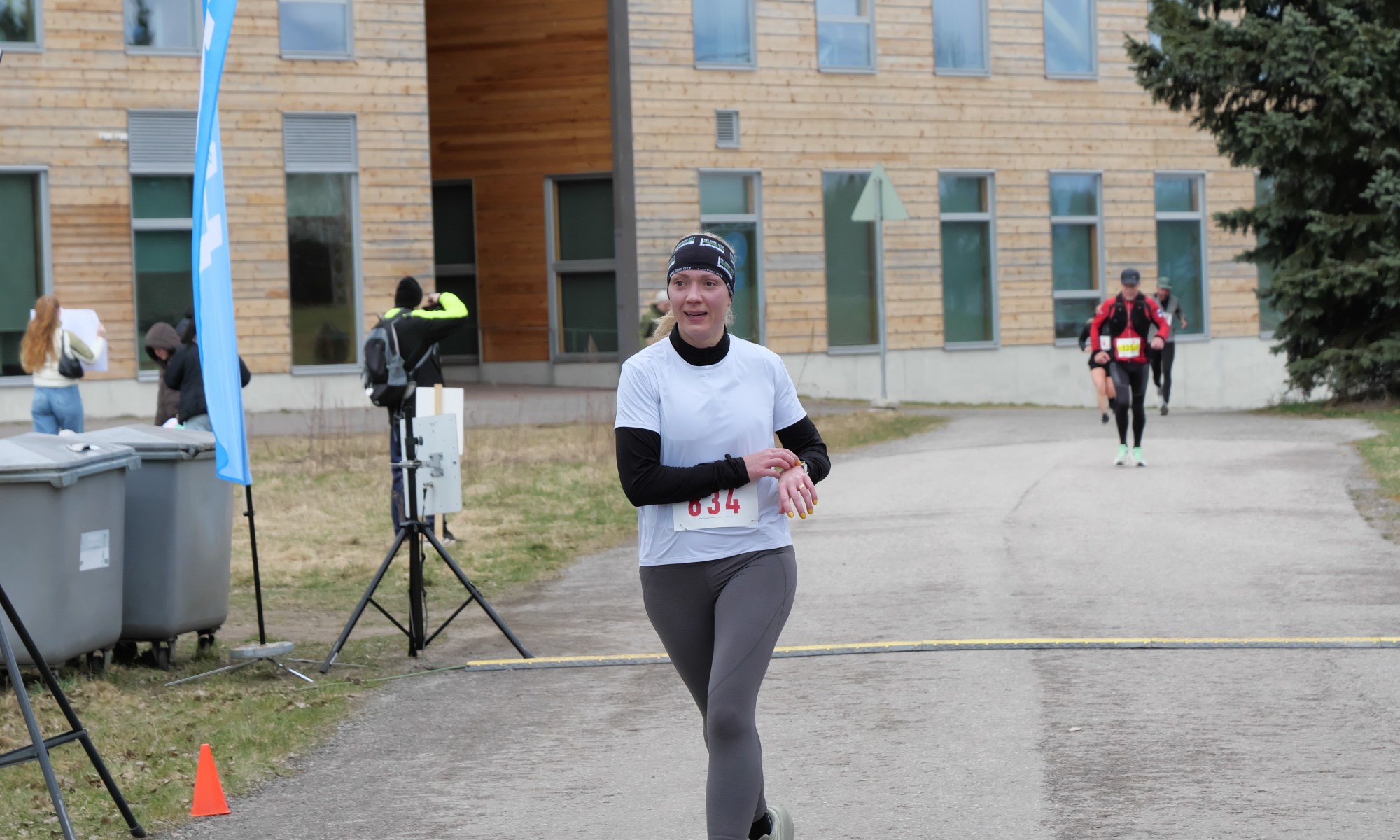 kymmenen kilometrin juoksija saapuu maaliin juoksutapahtumassa ja painaa juuri urheilukelloaan stoppiin