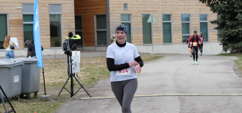 kymmenen kilometrin juoksija saapuu maaliin juoksutapahtumassa ja painaa juuri urheilukelloaan stoppiin