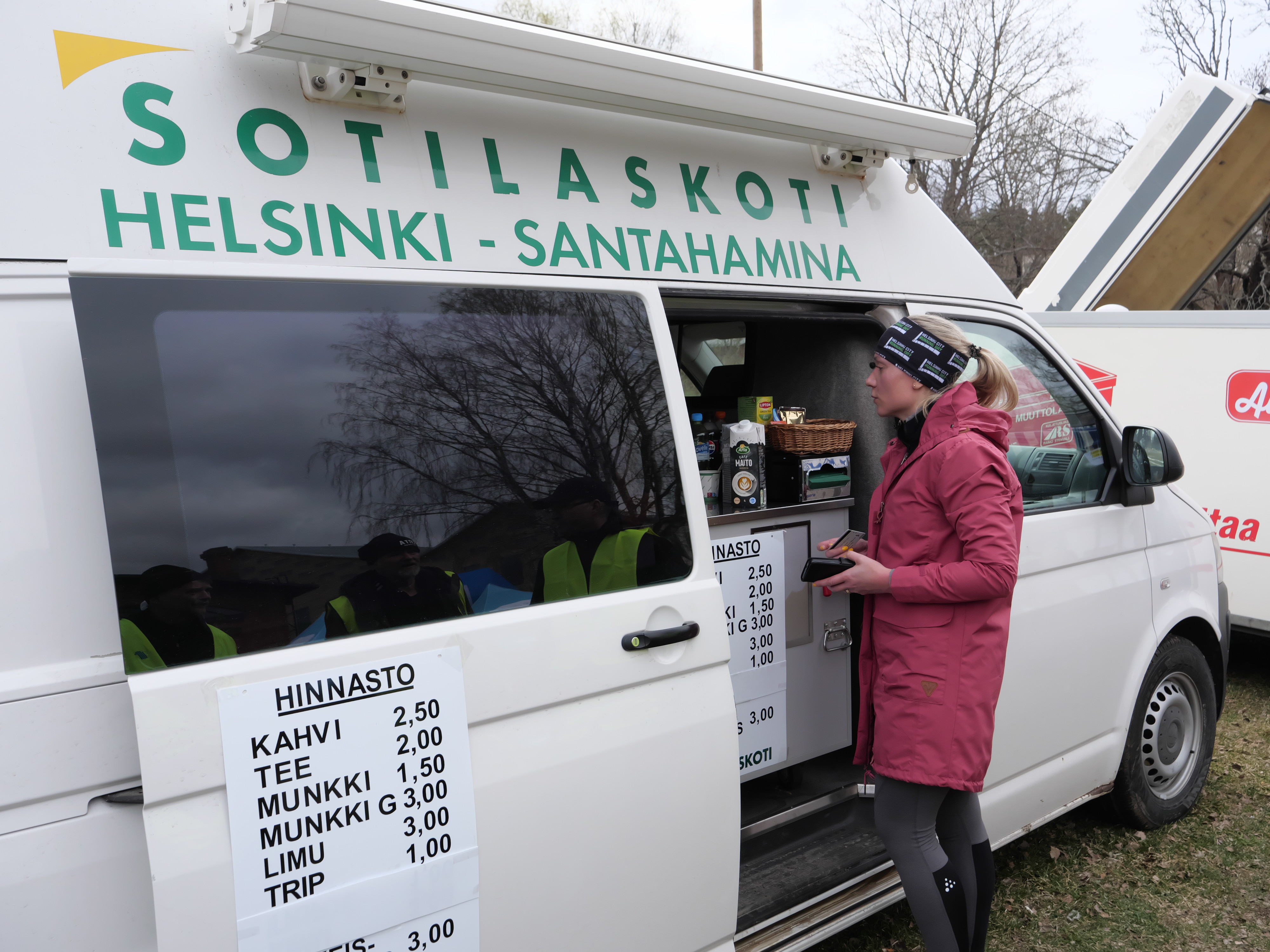 nainen seisoo myyntiauton edessa